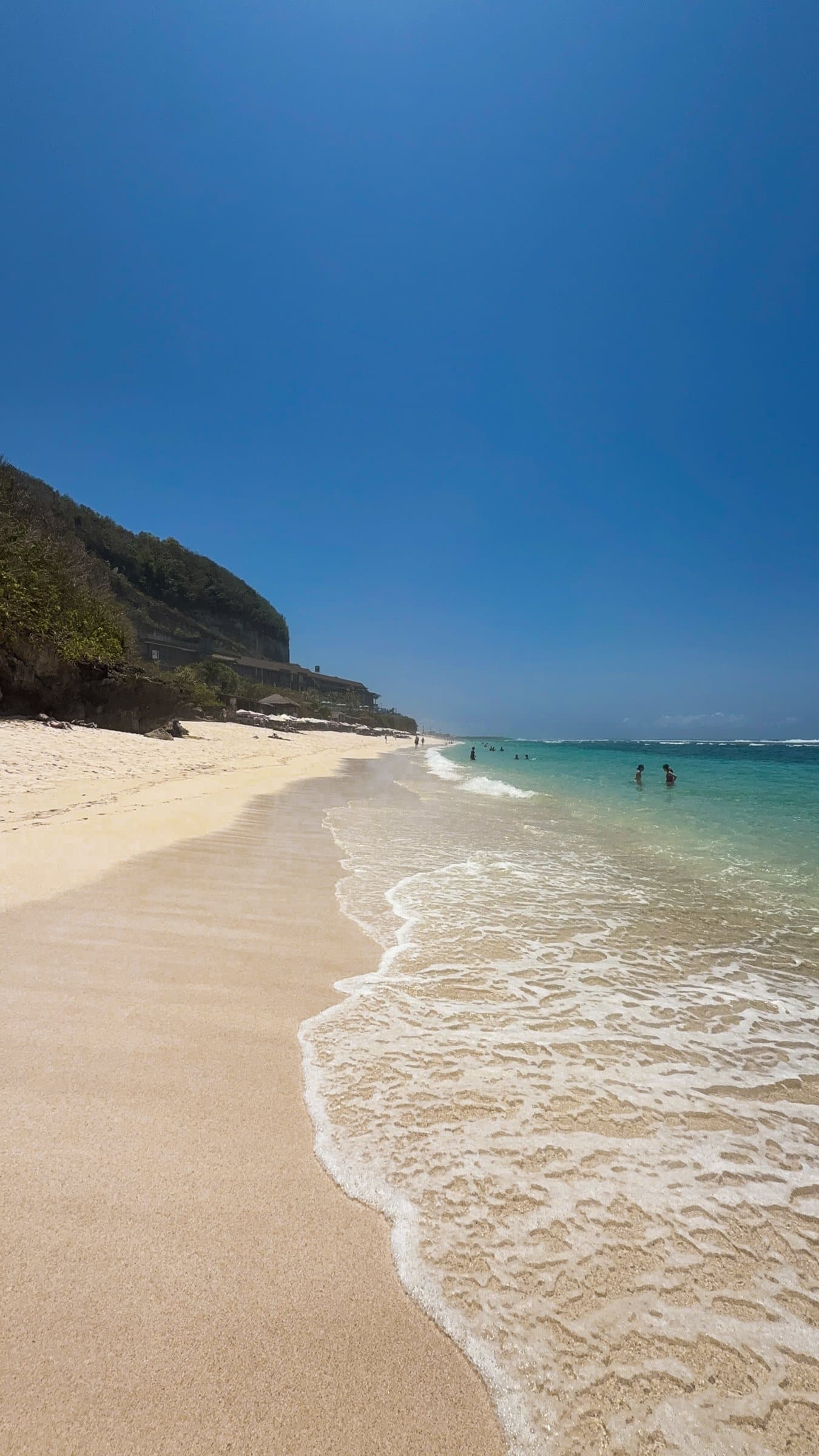 Empty beach curving under a headland, gentle waves on the sand