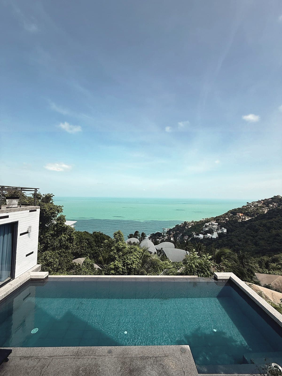 Plunge pool on a hillside looking over a forested bay to the sea
