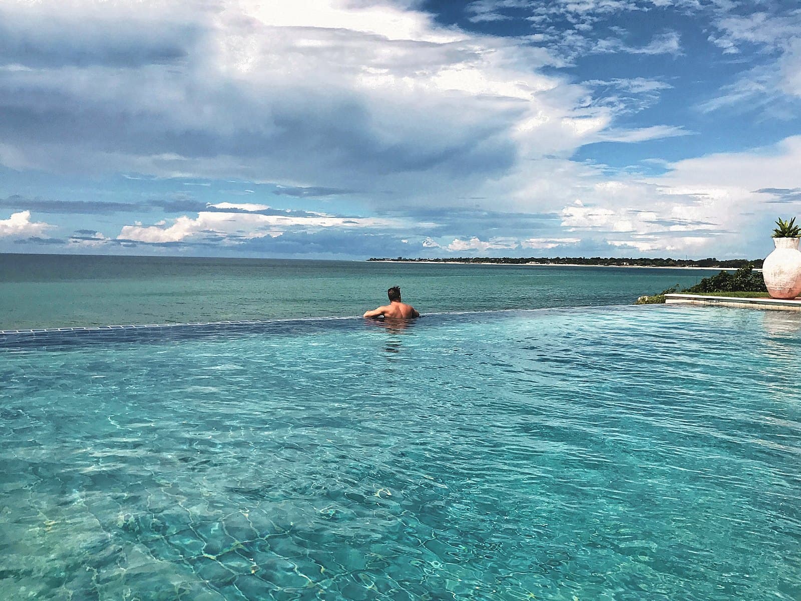 Swimmer in an infinity pool that meets the sea