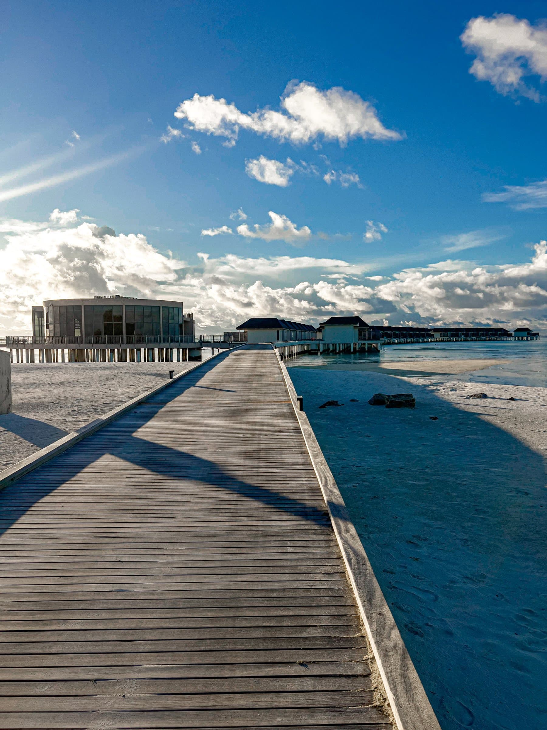 Long timber jetty leading to overwater buildings in soft morning light